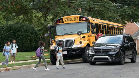 Children crossing in front of a bus.